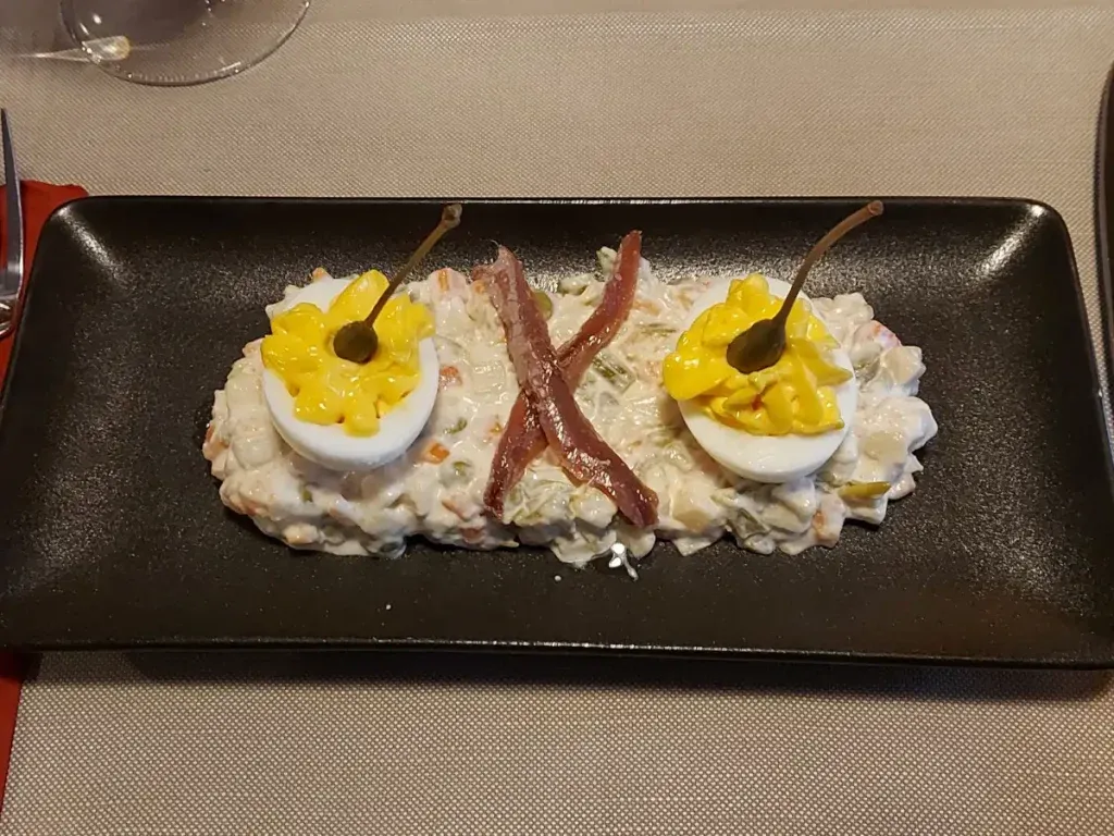 Russian salad from Ratskeller Bern: Vegetable and potato cubes in creamy sauce, garnished with egg, anchovies, and capers.