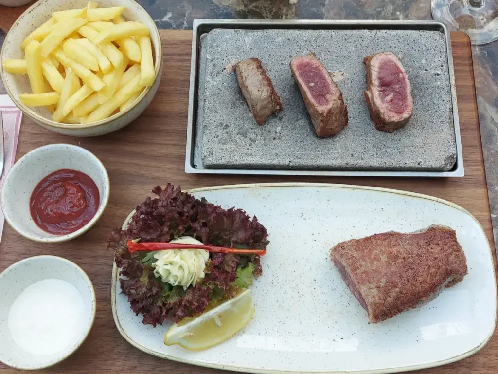 Entrecôte on hot stone with fries and sauces at Restaurant Celina Bern