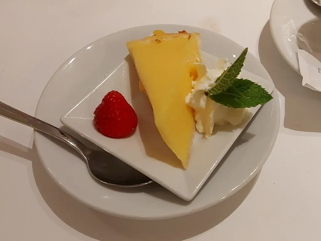 Small portion of tarte aux citrons garnished with strawberry, cream, and mint from Entrecôte Fédérale Bern.