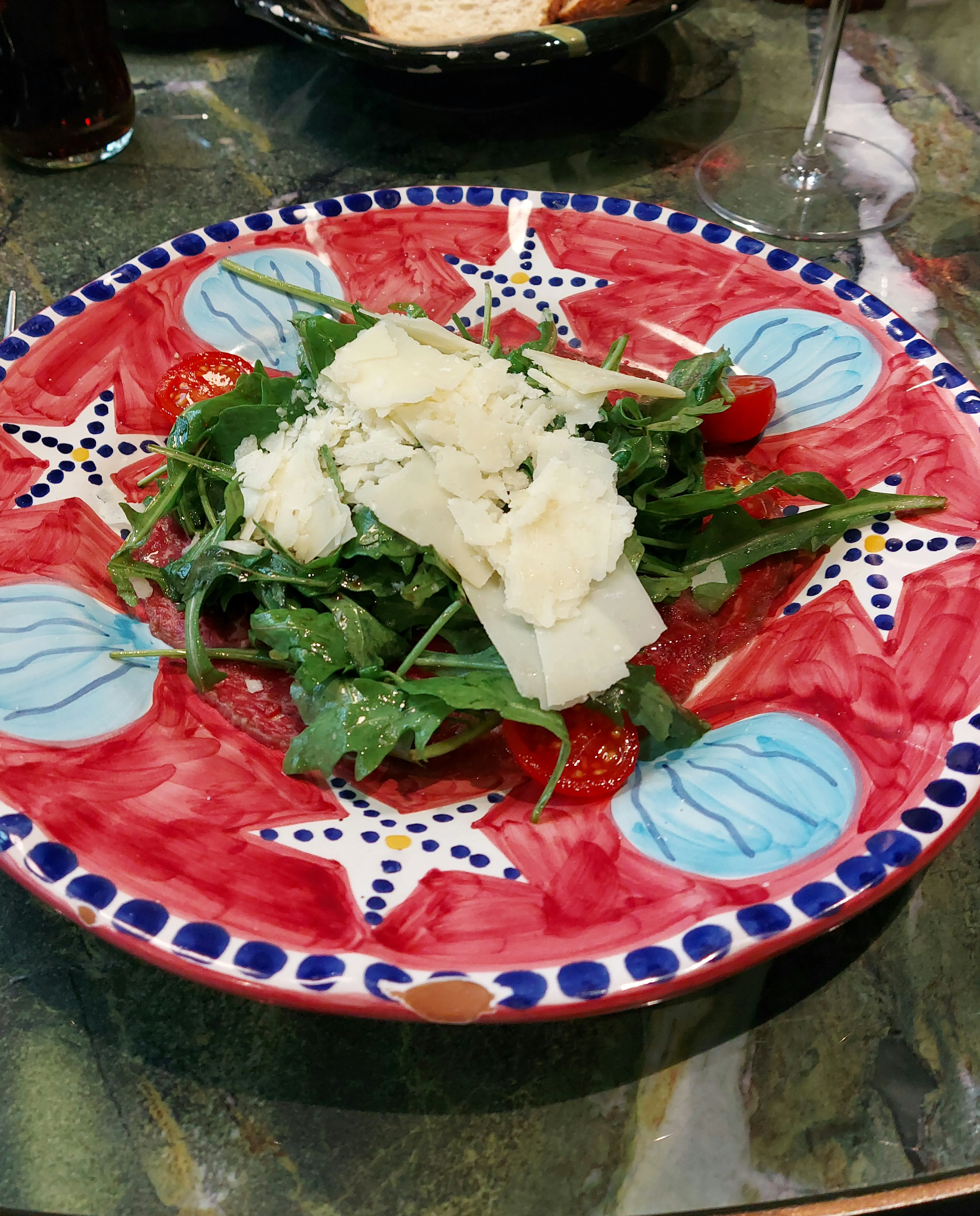 Carpaccio mit Rucola, Grana und Dressing in der Galleria Luce Bern – angerichtet auf einem weissen Teller