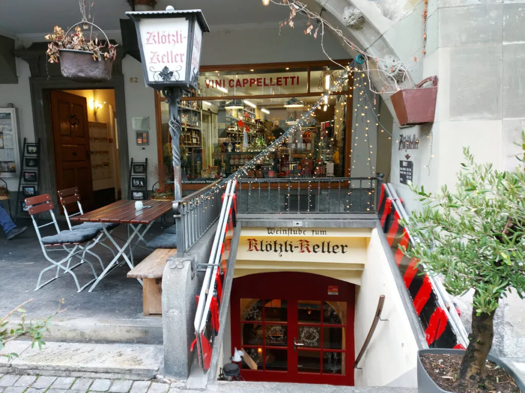 Kleine Terrasse unter den Berner Lauben neben der geöffneten Kellertür und der traditionellen Laterne des Klötzlikellers