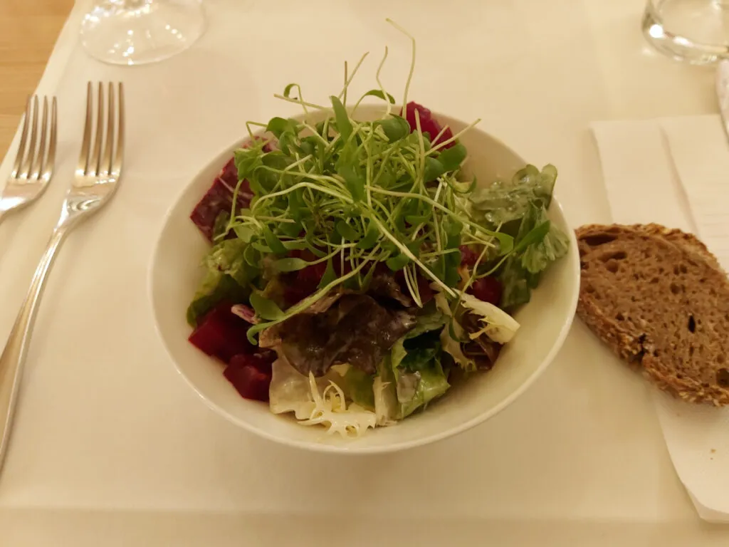 Ein kleiner grüner Blattsalat mit frischer Kresse garniert in einer weissen Porzellan-Schüssel