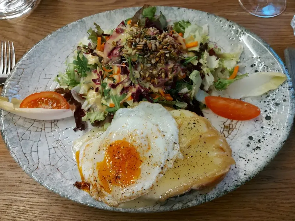 Käseschnitte mit Spiegelei und gemischtem Salat auf einem Teller