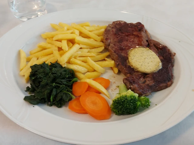 Sirloin steak with herb butter, fries, and vegetables at Warteck Bern